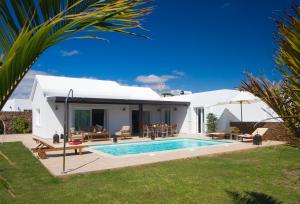 a backyard with a swimming pool and a house at Villa Coral in Puerto del Carmen