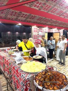 a group of people standing around a table with food at Beduin Star Trail Camp in Wadi Rum