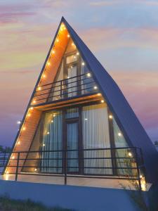 a triangle house with lights on it at dusk at Alagi Cottage at Bazaleti lake in Grigolaantkari