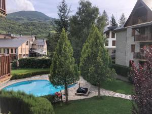 a swimming pool in a yard with trees and buildings at El Rincón del Alba in Benasque