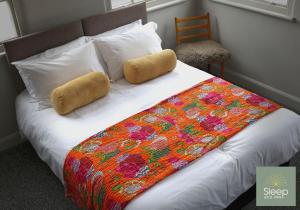 een bed met een kleurrijke deken en kussens erop bij Sleep Hotel in Worthing