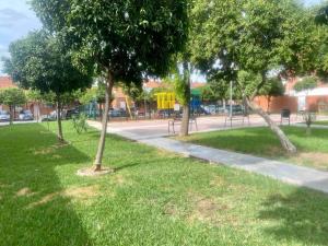 a park with trees in the grass and a sidewalk at Casa unifamiliar FIBES in Seville