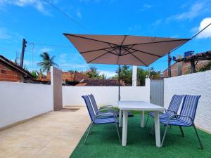 a table and chairs with an umbrella on a patio at Casa Areal Boipeba in Ilha de Boipeba