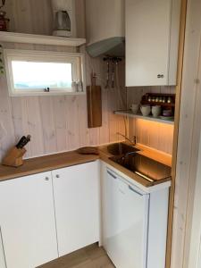 cocina con armarios blancos, fregadero y ventana en Nice whole year Cottage byThingvallavatn, en Veiðilundur
