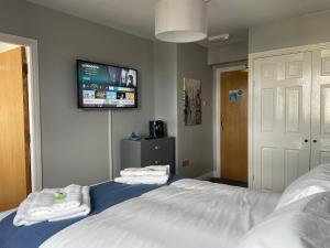 a bedroom with two beds and a tv on the wall at Feildens Arms Hotel in Blackburn