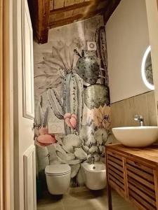 a bathroom with a toilet and a sink with a cactus wallpaper at CASA LITA con terrazzo in Ravenna