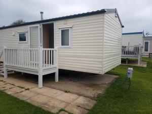 a white tiny house with a porch and a yard at Caravan Delta 2 Bedroom in Rhyl in Rhyl