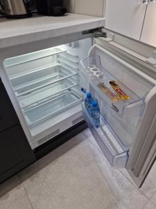 an empty refrigerator with two bottles of water in it at JUWEL Apartments Kraków Indyjski 29 in Kraków