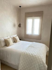 1 cama blanca en un dormitorio con ventana en El Rincón de Manuela, en Sarria