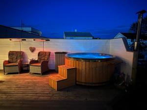 a hot tub on a patio with two chairs at Sauna House in Andenes