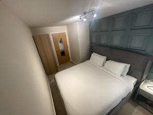 a small bedroom with a white bed with two pillows at The Retreat at Harlow in Potter Street