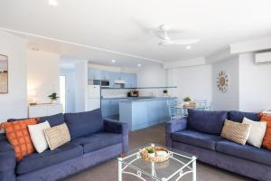 sala de estar con 2 sofás azules y cocina en Breakers 6, en Mollymook