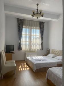 a bedroom with two beds and a chair and a television at Peja INN in Peje