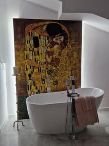a bath tub in a bathroom with a painting of a woman at Juwel Apartments Kraków z widokiem na Wawel 47 in Krakow