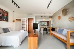 een slaapkamer met een bed, een bank en een tv bij Refúgio Wyrá in Itacaré