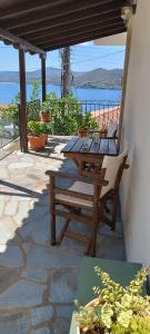 a wooden table and chairs on a patio with the ocean at Avli Apartments in Pyrgadikia