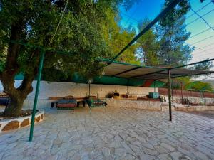 a pavilion with a table and chairs under a tree at Oak Farm مزرعة الملّول in Ajloun
