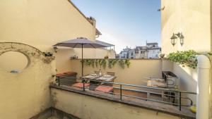 - Balcón con mesa y sombrilla en 3 Terrace Apartment In Florence, en Florencia
