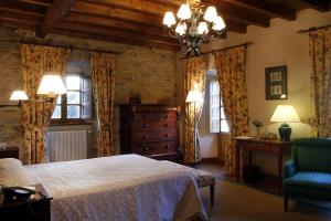 a bedroom with a bed and a chair and windows at Hotel Rural Palacio de Prelo in Boal