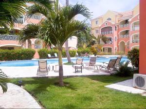 a resort with chairs and a palm tree next to a swimming pool at El Dorado Condo 208A in Punta Cana