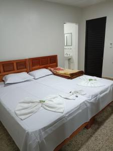 a large white bed with white sheets and bows at Dom Del'Gaudio Melhor lugar do mundo in Foz do Iguaçu