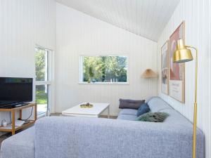 uma sala de estar com um sofá azul e uma televisão em Holiday home Juelsminde XLIII em Juelsminde