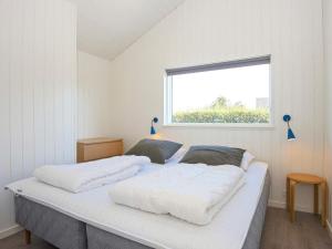 um quarto com uma cama com lençóis brancos e uma janela em Holiday home Juelsminde XLIII em Juelsminde
