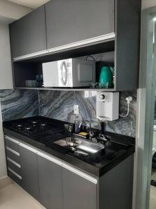 a kitchen with a sink and a microwave at Luxo e conforto in Goiânia