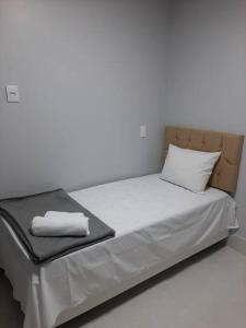 a bed in a room with a white wall at Luxo e conforto in Goiânia