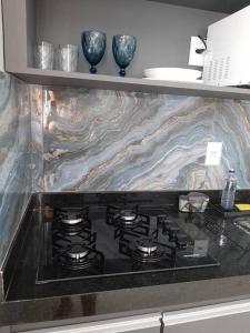 uma placa de fogão numa cozinha com uma bancada em mármore em Luxo e conforto em Goiânia