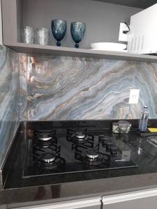 a stove top in a kitchen with a marble counter top at Luxo e conforto in Goiânia +12 photos
