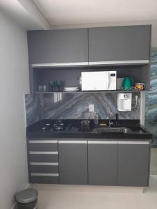 a kitchen with white cabinets and a black counter top at Luxo e conforto in Goiânia