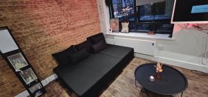a living room with a black couch and a table at Cosy studio flat in North London in London