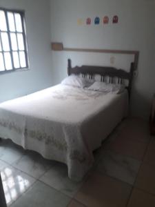 Schlafzimmer mit einem Bett mit weißer Bettwäsche und einem Fenster in der Unterkunft Casa dos corais in Vila Velha