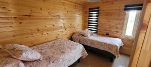 1 dormitorio con 2 camas en una cabaña de madera en Cabañas Santa Elena en Pelluhue