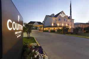 een gebouw met een bord voor een landhuis bij Country Inn & Suites by Radisson, Covington, LA in Covington