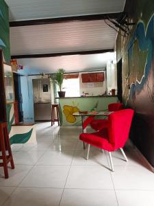 uma sala de estar com uma mesa e cadeiras vermelhas em Hostel Alto Astral - Fonte em Morro de São Paulo