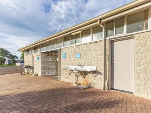 un edificio con una puerta blanca y un fregadero. en NRMA Portland Bay Holiday Park, en Portland