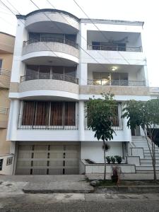 a white building with balconies and a tree in front of it at Apartamento en el ingenio 2 in Cali