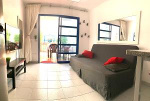 a living room with a couch with red pillows on it at Bungalow Helena in Maspalomas +21 photos