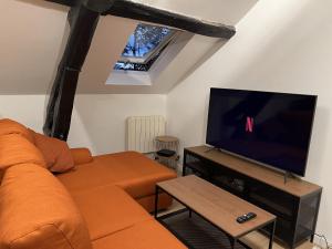 a living room with an orange couch and a flat screen tv at Quality Suites - Proche Versailles Paris - Parking Gratuit in Saint-Germain-en-Laye