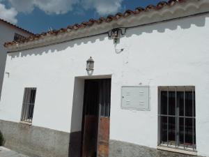 un edificio blanco con puerta y luz de la calle en La casita en la Alcornocosa -Sevilla, en Sevilla