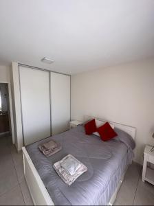 1 dormitorio con 1 cama grande con almohadas rojas en Hermoso departamento completo minimalista en Barrio cerrado con estacionamiento en Guaymallen