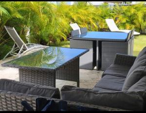a patio with two tables and chairs and palm trees at Ocean Motion Rental Casa en la playa con piscina cerca Yunque y VSjuan in Loiza