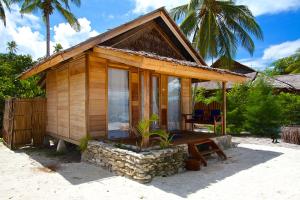 małą drewnianą kabinę ze stołem i ławką w obiekcie Agusta Eco Resort w mieście Pulau Mansuar
