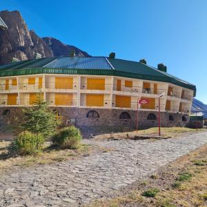 ein großes Gebäude mit einem grünen Dach vor einem Berg in der Unterkunft Aires de Montaña - Departamento en Los Penitentes, Mendoza in Los Penitentes