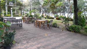 a patio with tables and benches and palm trees at Victory view rayong beach in Ban Chamrung