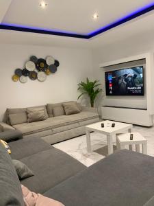 sala de estar con sofá y TV de pantalla plana en Aroeira Tropical Villa, en Charneca