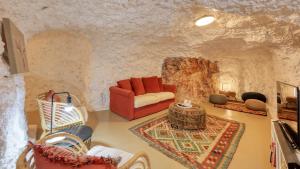 a living room with a red couch in a stone wall at Daybreak Dugout Luxury Underground House in White Cliffs