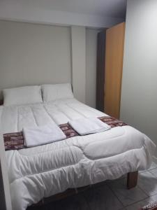 een bed met witte lakens en kussens erop bij Ataraxia Light House in Cuzco